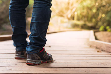 Close-up shot of a persons boots walking along a wooden path in the bushの写真素材
