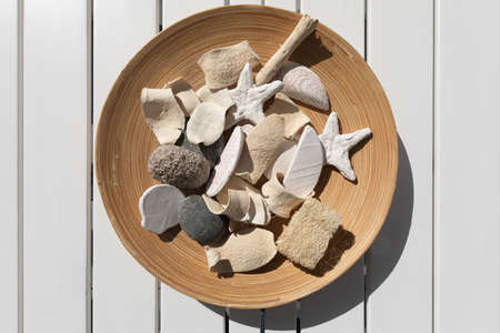 Overhead shot of wooden plate with rocks inside on white wooden background
