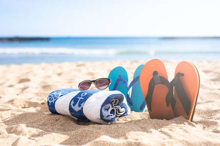Beach shoes, towel and sunglasses on the sand on a beachの写真素材