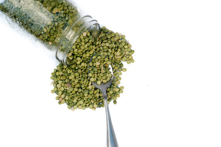 Green peas spilling out of a mason jarの写真素材