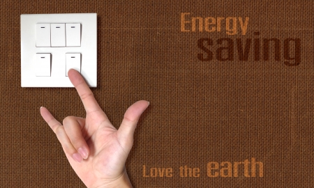 energy saving theme the act of hand in symbol of love switch off the light on the wood board wall の写真素材