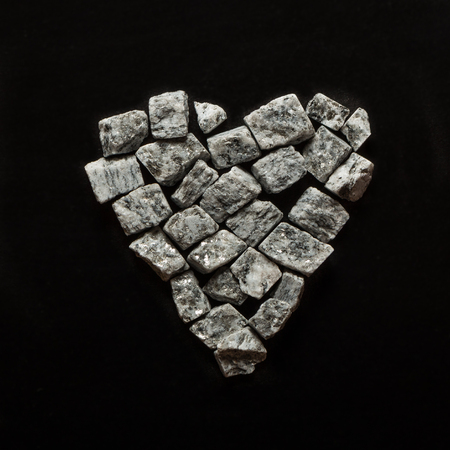 beautiful crushed granite gray on a black background, stone heartの写真素材