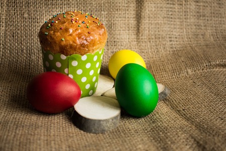 Colored Easter eggs and a festive cake, rustic backgroundの写真素材