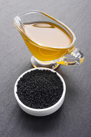 grains of black cumin and oil on the rustic background.の写真素材