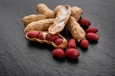 fresh peanuts on a dark stone background.の写真素材