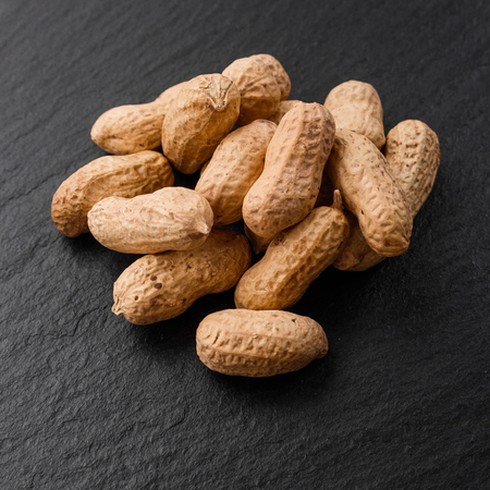 fresh peanuts on a dark stone background.