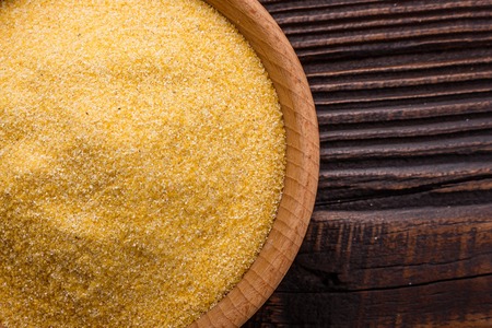 aw Italian corn porridge polenta on a rustic wooden background.