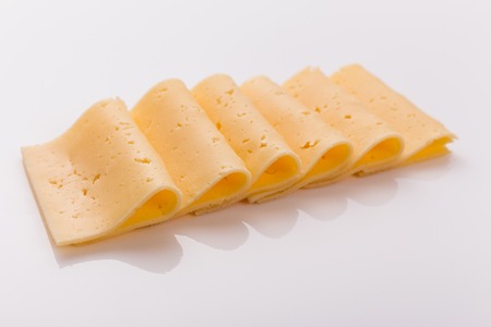 Piece and slices of cheese on a white background.