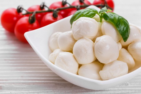 Mozzarella tomatoes and basil on a wooden rustic background.
