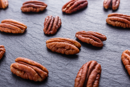 delicious pecan nuts on a dark stone background.