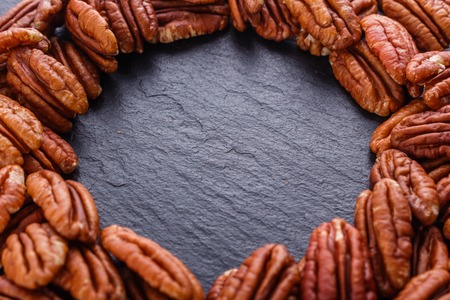 delicious pecan nuts on a dark stone background.