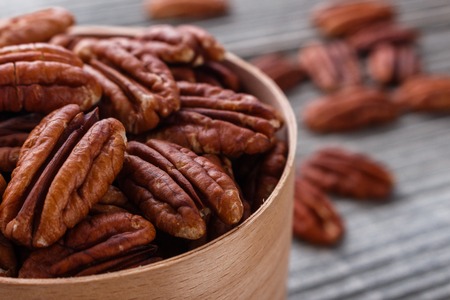 delicious pecan nuts on a rustic wooden background.