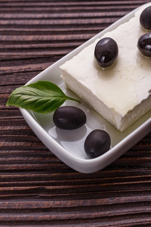 A piece of feta cheese on a wooden rustic background.の写真素材
