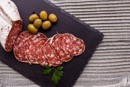 Saucisson sec delicious french salami on a wooden background.