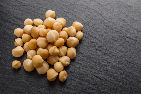 delicious macadamia nuts on a dark stone background.の写真素材