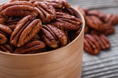 delicious pecan nuts on a rustic wooden background.