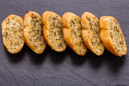 fragrant garlic bread on a dark stone plate.の写真素材