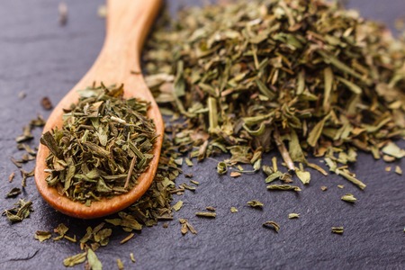 dried tarragon and essential oil on a dark stone background.の写真素材