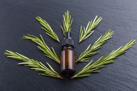 Rosemary essential oil on dark stone background.の写真素材