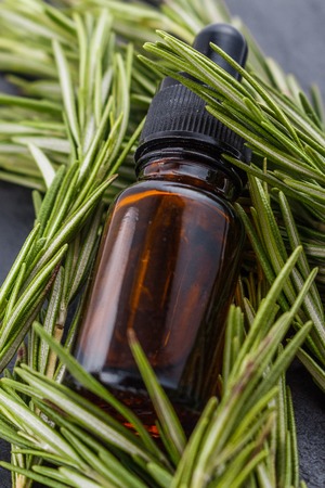 Rosemary essential oil on dark stone background.の写真素材