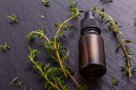 essential oil of thyme on a dark stone background.の写真素材