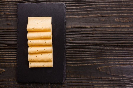 Piece and slices of cheese on a wooden background.の写真素材