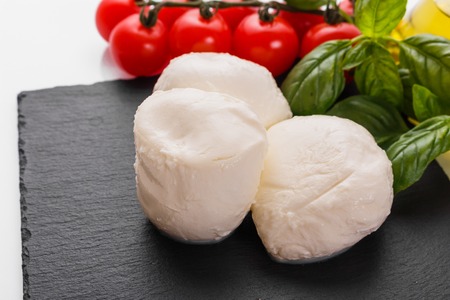 Mozzarella tomatoes and basil on a white background.