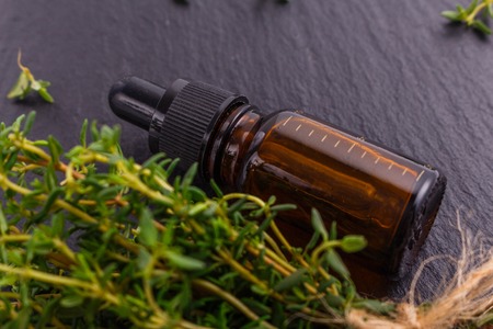 essential oil of thyme on a dark stone background.の写真素材