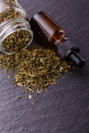 dried tarragon and essential oil on a dark stone background.の写真素材