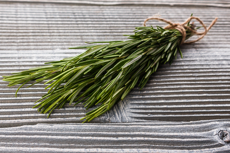 Rosemary essential oil on a gray wooden rustic background.の写真素材