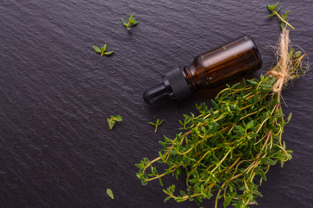 essential oil of thyme on a dark stone background.の写真素材