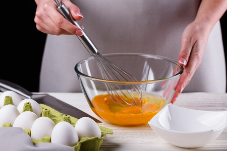 young woman in a gray aprons breaks the eggs.の写真素材