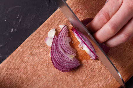 young woman in a gray aprons cuts red onion.の写真素材