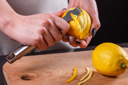 young woman in a gray aprons cuts lemon zest.の写真素材