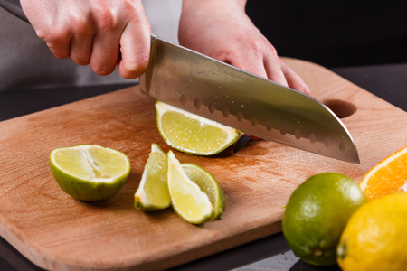 young woman in a gray aprons cut lime.の写真素材