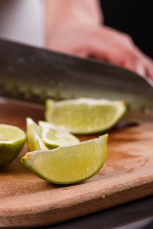 young woman in a gray aprons cut lime.の写真素材