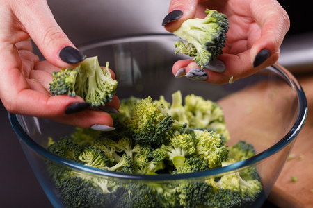young woman in a gray apron roasts cauliflower broccoli.の写真素材