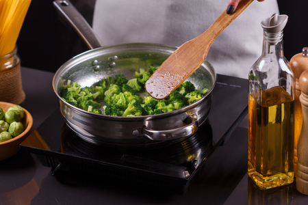 young woman in a gray apron roasts cauliflower broccoli.の写真素材
