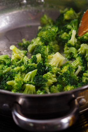young woman in a gray apron roasts cauliflower broccoli.の写真素材