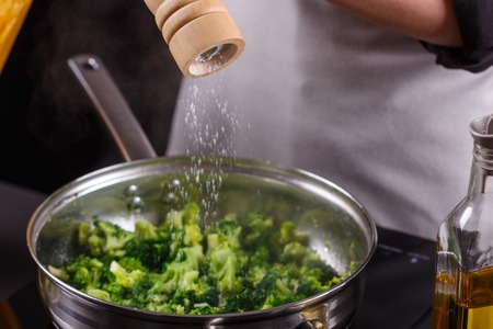 young woman in a gray apron roasts cauliflower broccoli.の写真素材