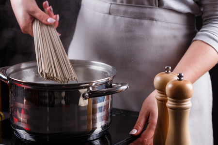 young woman in a gray aprons is preparing a noodle soba.の写真素材