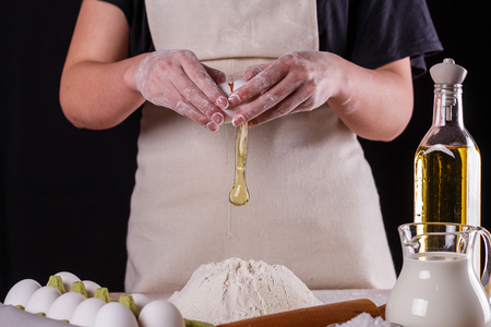 young woman in an apron slips eggs to a dough.の写真素材