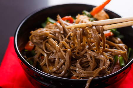 Buckwheat noodle in a black bowl on chicken fillet.の写真素材