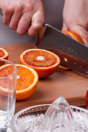 young woman in a gray apron cuts blood orange.の写真素材