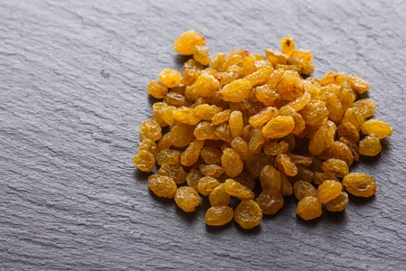 golden raisins on a dark stone background.の写真素材