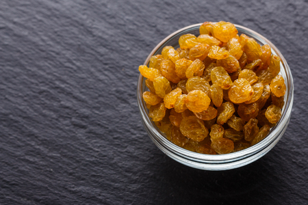 golden raisins on a dark stone background.の写真素材