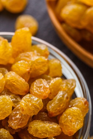 golden raisins on a dark stone background.の写真素材