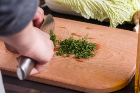 young woman slicing herbs in a gray apron.の写真素材