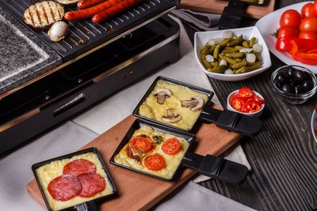 young woman is preparing a traditional Swiss cheese raclette.の写真素材