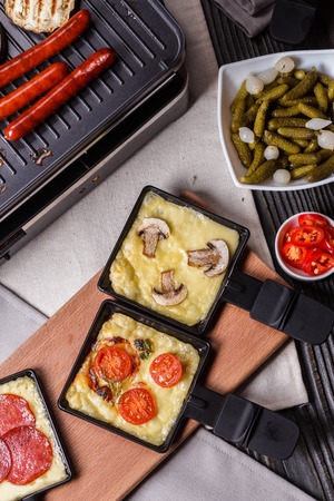 young woman is preparing a traditional Swiss cheese raclette.の写真素材